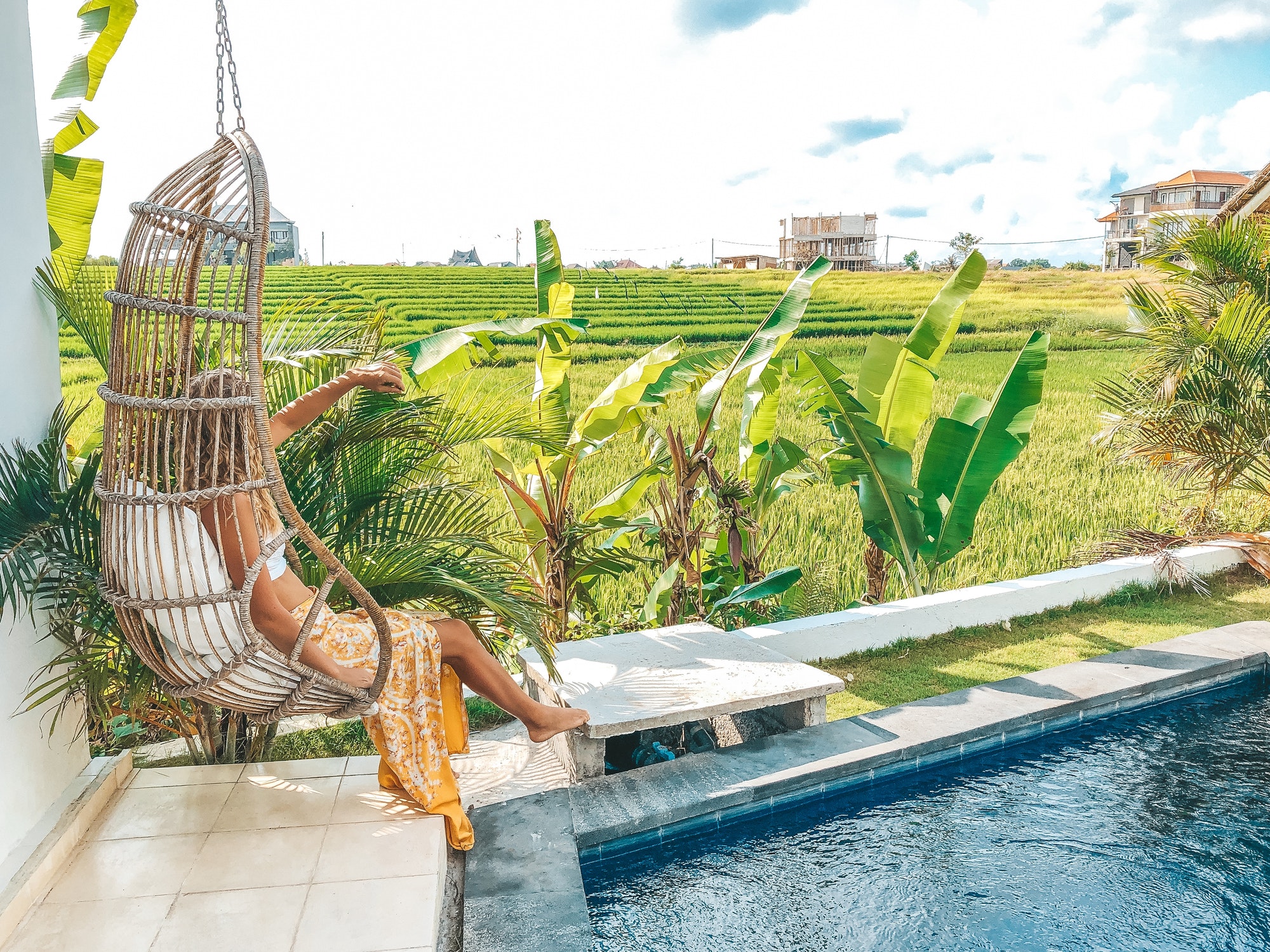 Woman relaxing in the swinging chair by the rice fields