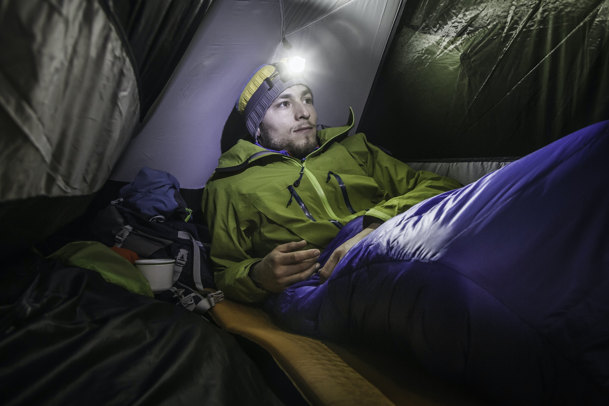 Young male hiker in tent on Klammspitze mountain, Oberammergau, Bavaria, Germany